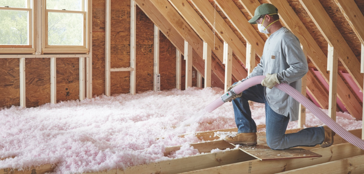 Canadian Insulation Experts technician blowing fibreglass insulation into an attic floor in Toronto