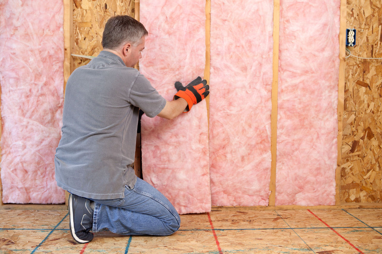 Canadian Insulation Experts installer fitting fibreglass batt insulation between wall studs in Toronto